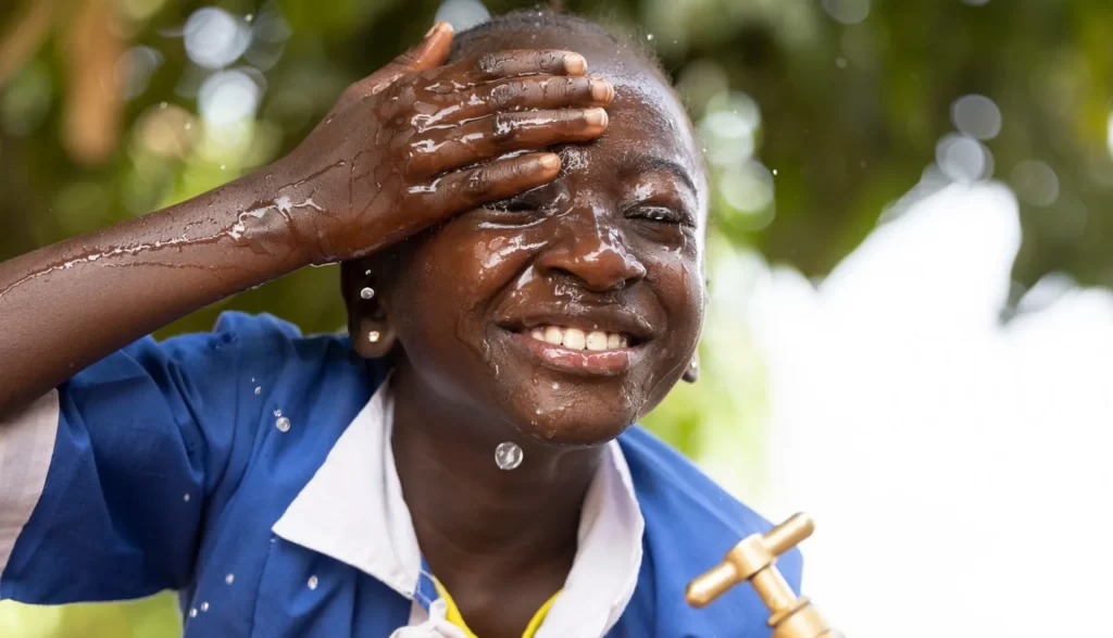 Second grade student Fatou (8) washes her face in clean water at a ChildFund-installed tap at her school.
